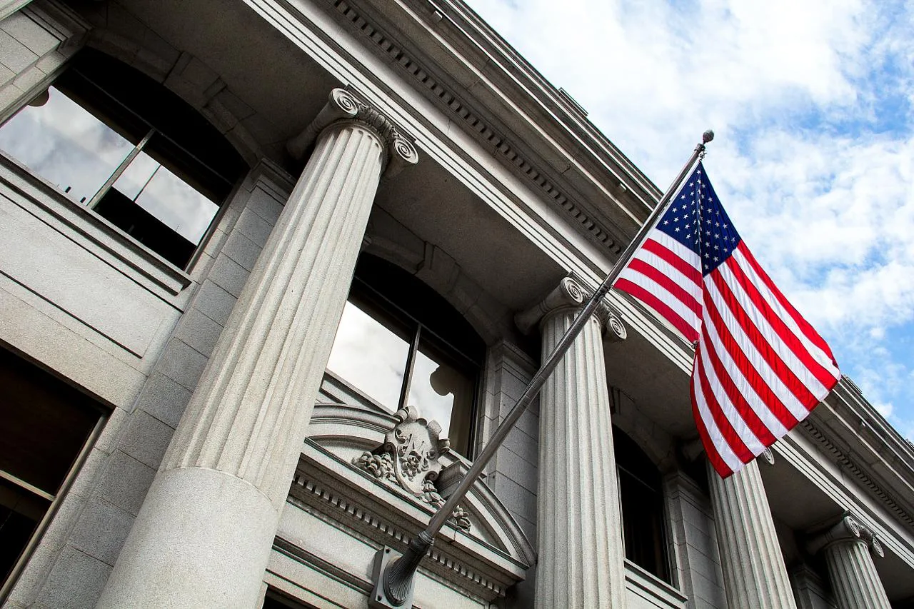 US flag flying outside a neoclassical government courthouse building