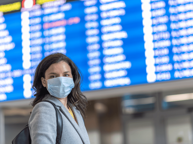 woman at airport in front of departures and arrivals screens