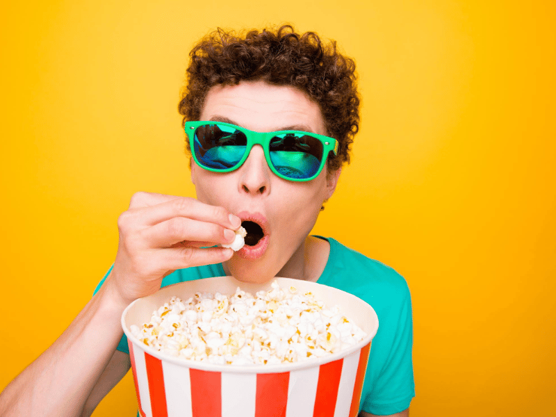 man wearing sunglasses eating popcorn